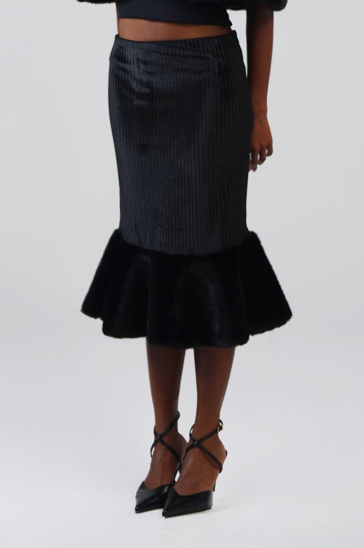 Close-up of the ribbed velvet and faux fur flounce on the black midi skirt, three-quarter view