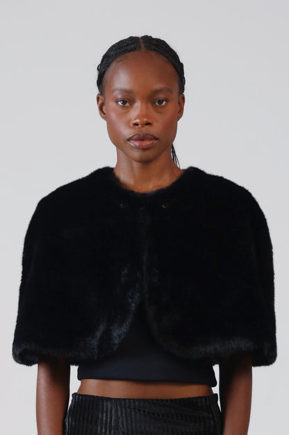 Close-up of the black faux fur capelet from the front, showing the round neckline and rounded front edges