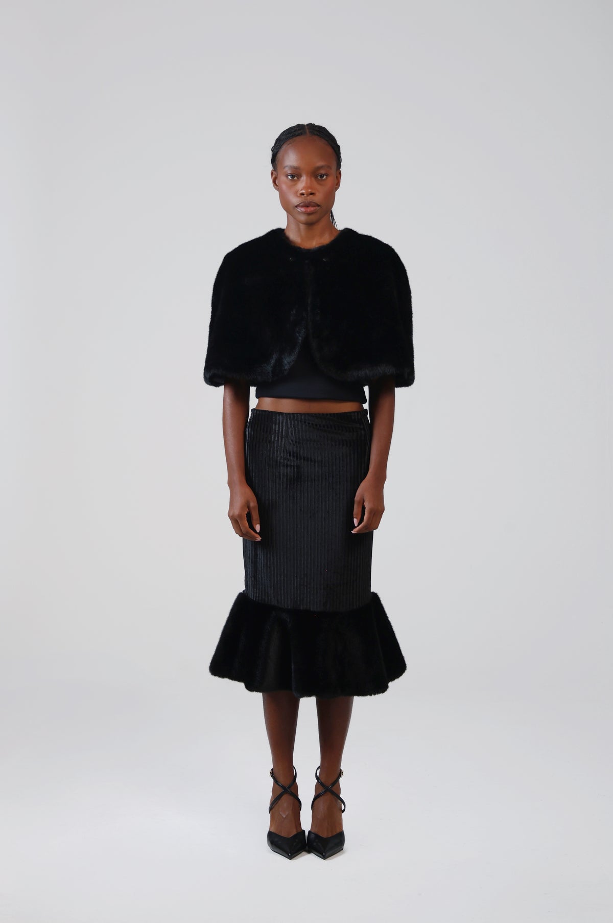 Black faux fur capelet, front view on model, showing the elbow-length drape and rounded front edges