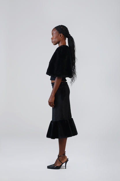 Black velvet midi skirt with faux fur flounce, side view on model, showing the fitted hip and flared hem