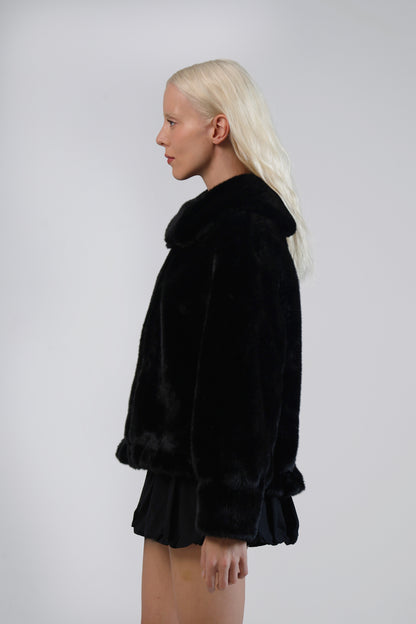 Jinnette black faux fur jacket, side profile on model, showing the collar, deep cuffs and peplum hem