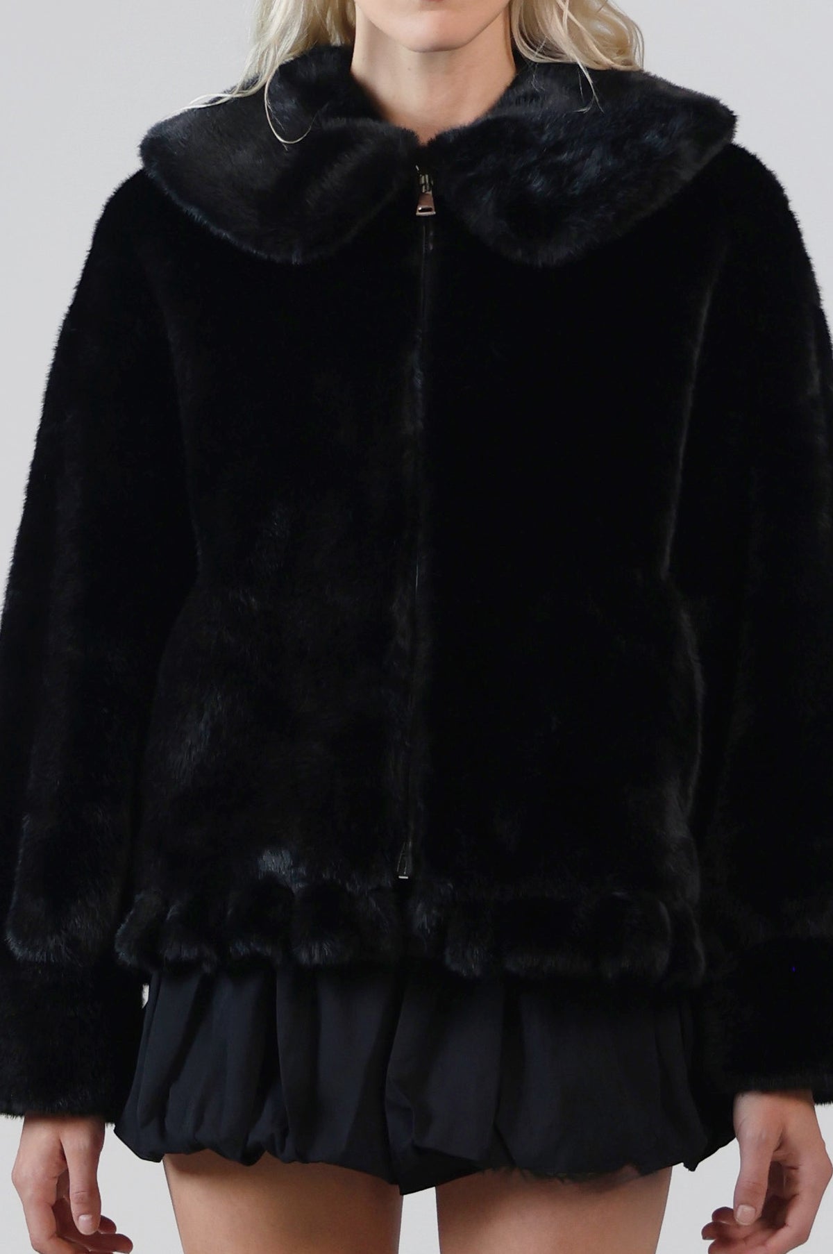 Close-up of the Jinnette jacket's Peter Pan collar, front zip and gathered peplum hem in black faux fur