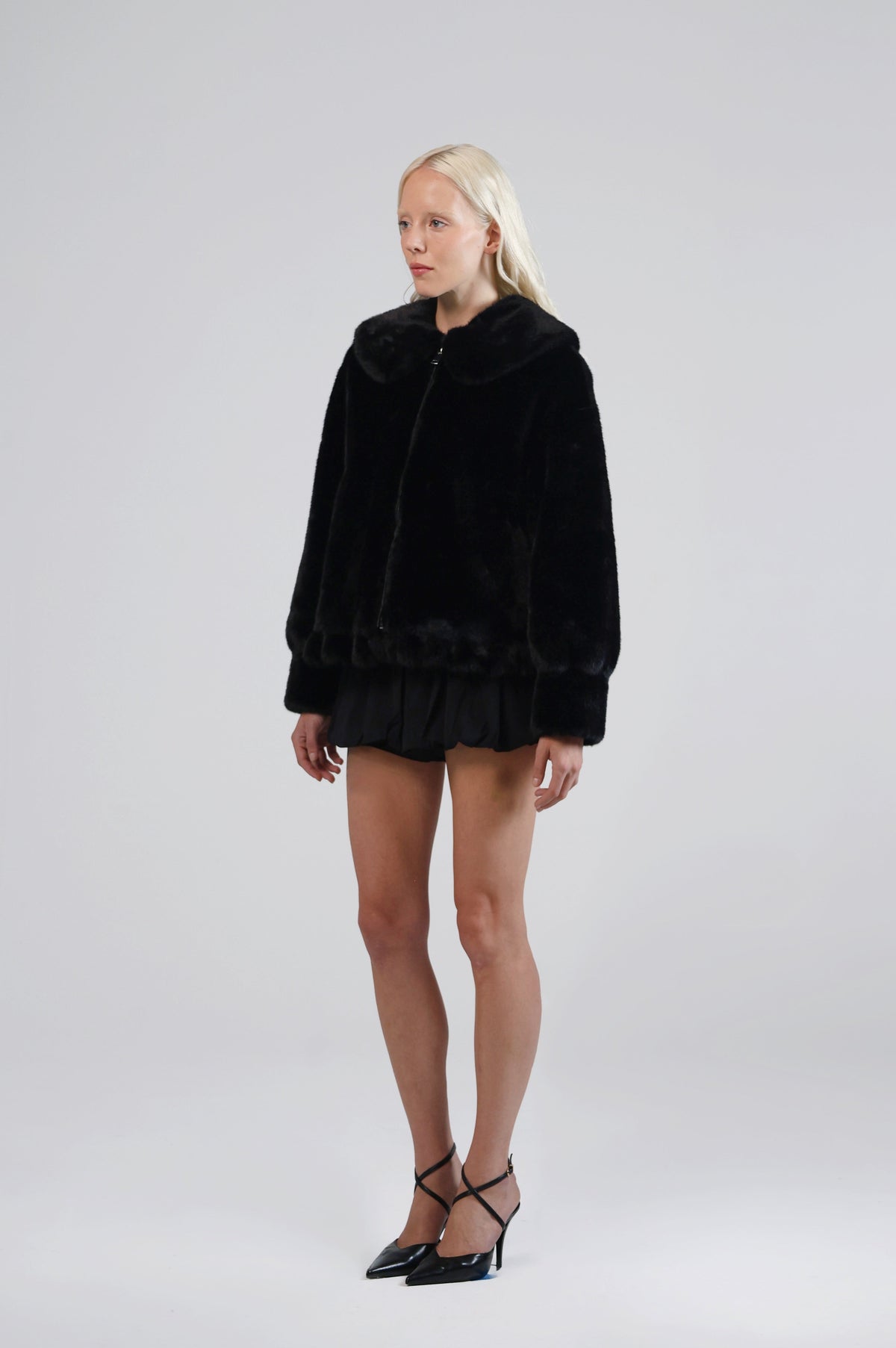 Jinnette black faux fur jacket with a relaxed fit and wide sleeves, three-quarter view on model