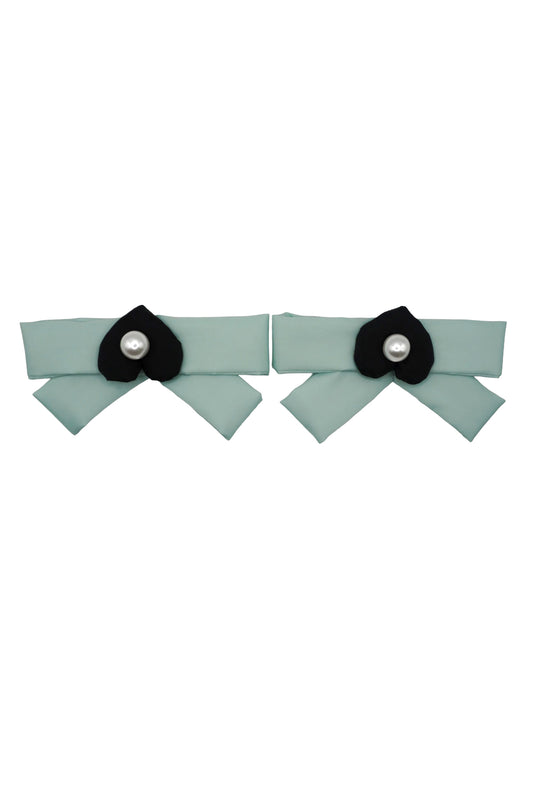 Pair of mint green bow charms, each centered with a black mamu heart logo and a pearlescent bead
